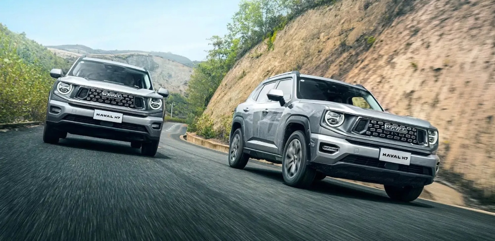 Dos camionetas GWM Haval H7 siendo conducidas por carretera entre montañas.